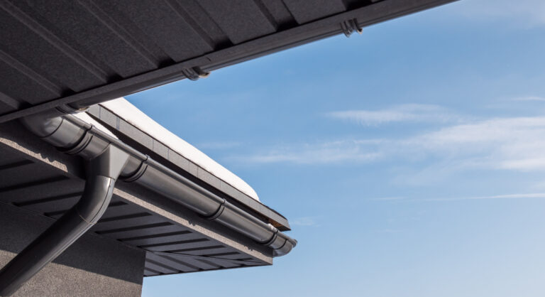 The corner of the roof with a drainage system, on the roof lies snow